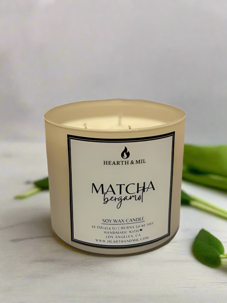 Matcha bergamot candle with a label on a light pink background