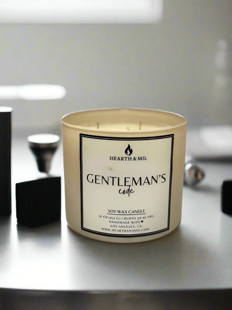 Candle labeled 'Gentleman's Code' by Hearth & Mil on a light pink background