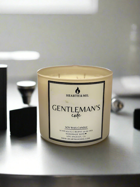 Candle labeled 'Gentleman's Code' by Hearth & Mil on a light pink background