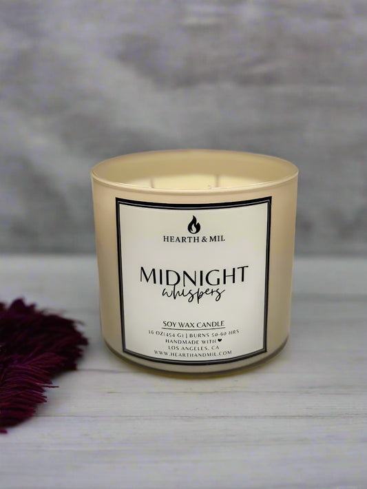 Candle with 'Midnight Whispers' label on a light pink background
