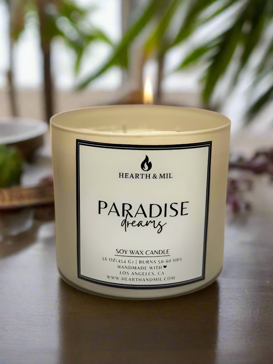 Candle with 'Paradise Dreams' label on a light pink background