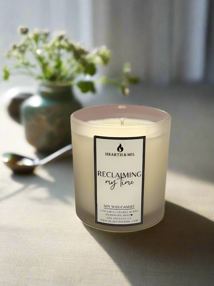 Candle with a label on a white surface and pink background