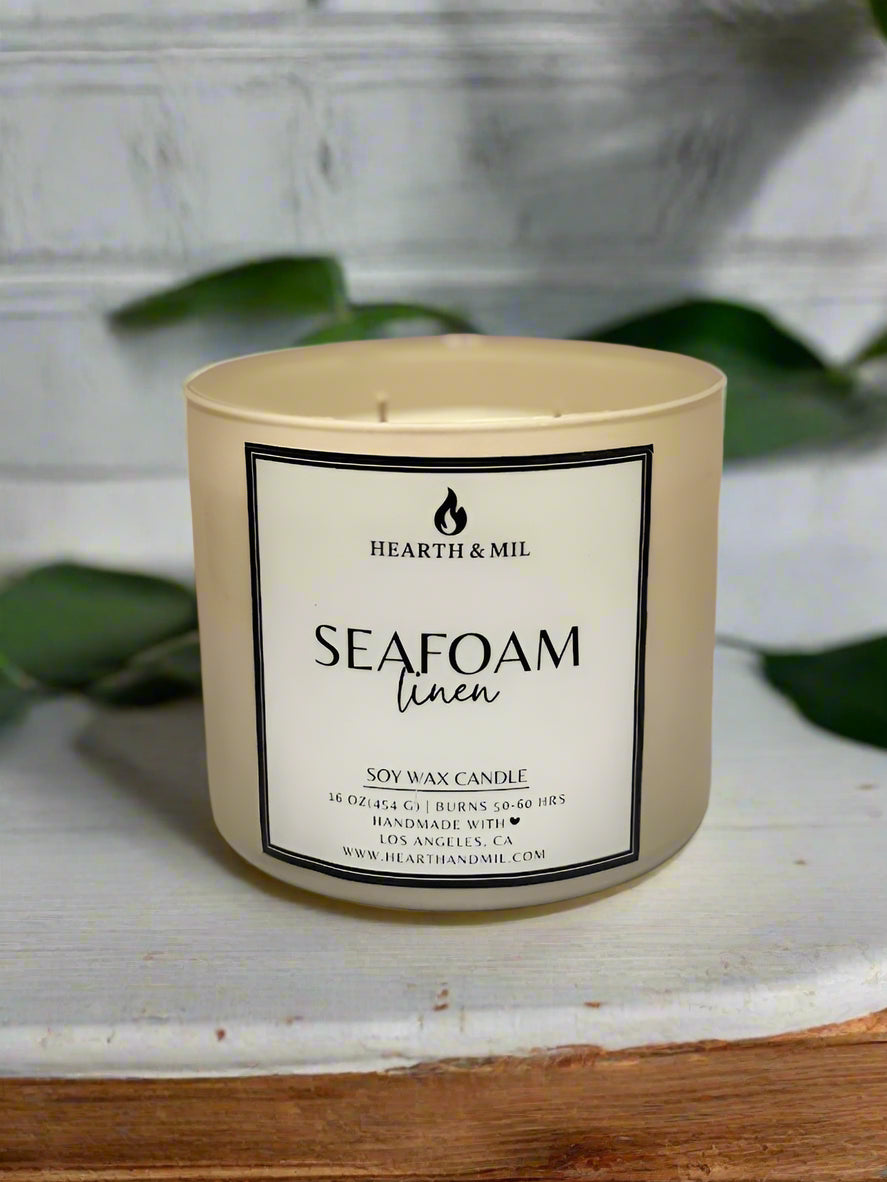 Candle labeled 'Seafoam Linen' by Hearth & Mil on a light background