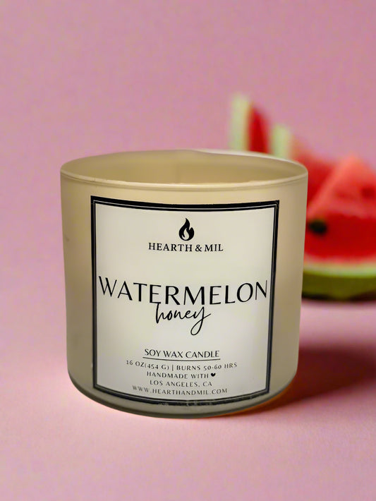 Candle labeled 'Watermelon Honey' by Hearth & Mil on a light pink background